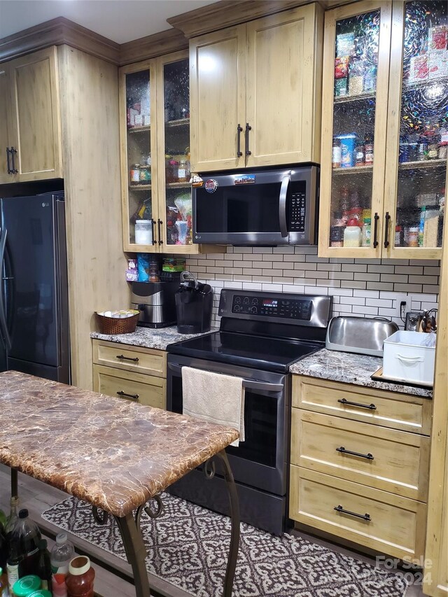 kitchen with light brown cabinets, backsplash, light stone countertops, and stainless steel appliances