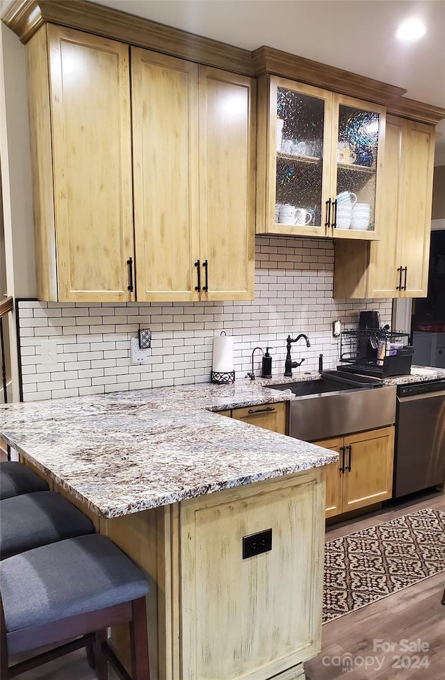 kitchen featuring light brown cabinets, light stone countertops, light wood-type flooring, and decorative backsplash