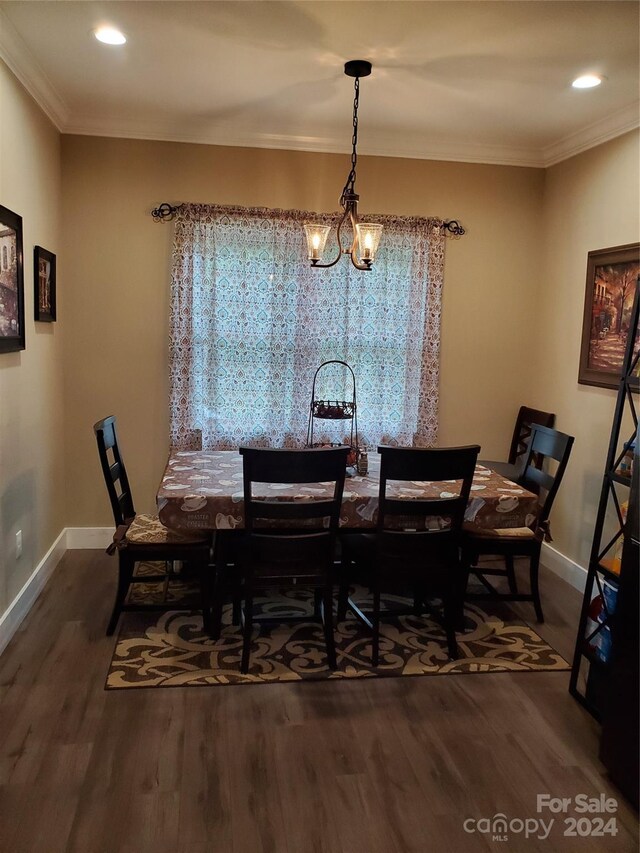 dining area with ornamental molding, an inviting chandelier, and dark wood-type flooring