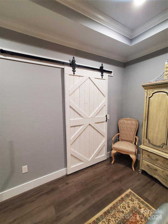 sitting room featuring a barn door, crown molding, a tray ceiling, and dark wood-type flooring