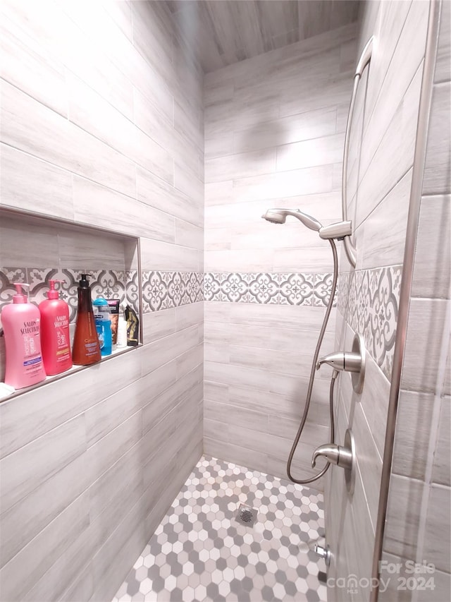 bathroom with a tile shower and tile walls