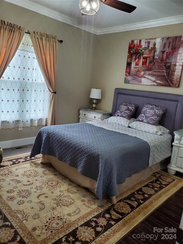 bedroom featuring wood-type flooring, ceiling fan, and crown molding