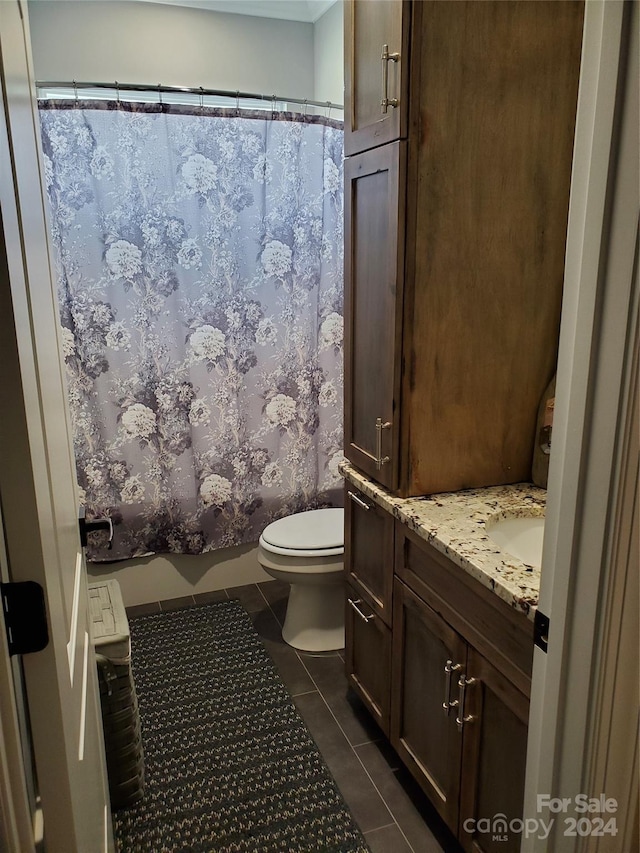 bathroom with walk in shower, vanity, toilet, and tile patterned floors