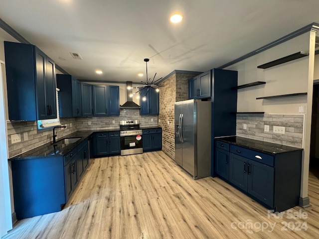 kitchen featuring blue cabinets, hanging light fixtures, sink, wall chimney exhaust hood, and appliances with stainless steel finishes