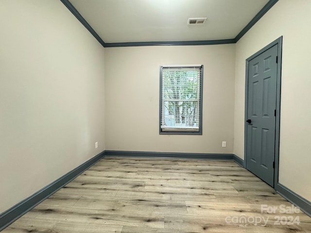 spare room featuring crown molding and light hardwood / wood-style flooring