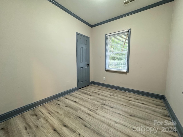 unfurnished room featuring light hardwood / wood-style floors and crown molding