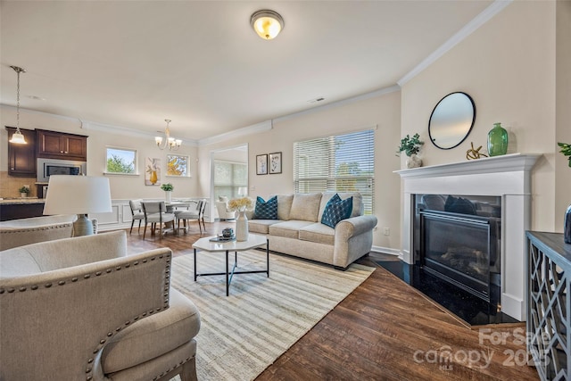 living room featuring wood finished floors, a high end fireplace, an inviting chandelier, crown molding, and baseboards