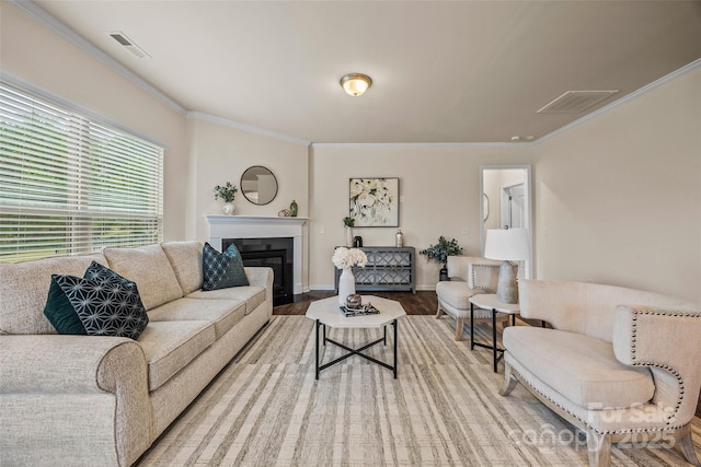 living room featuring visible vents, crown molding, a glass covered fireplace, and wood finished floors