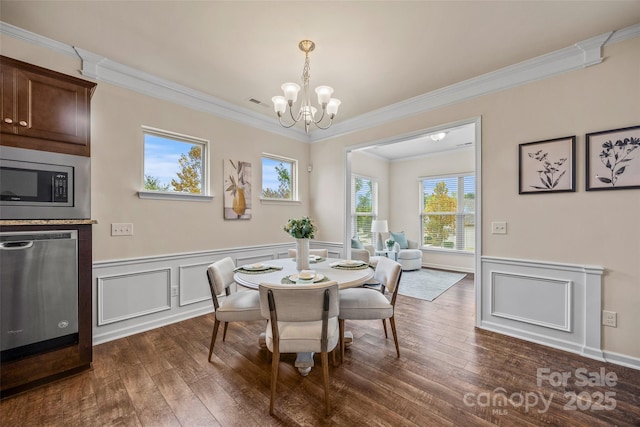 dining area featuring a notable chandelier, wainscoting, dark wood-style flooring, and ornamental molding