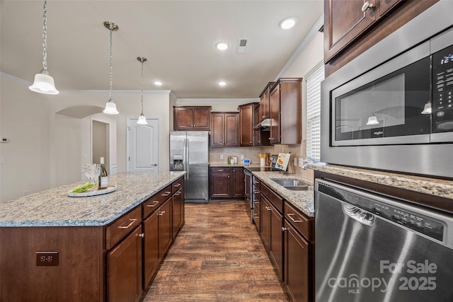 kitchen featuring tasteful backsplash, a kitchen island, dark wood-type flooring, appliances with stainless steel finishes, and arched walkways