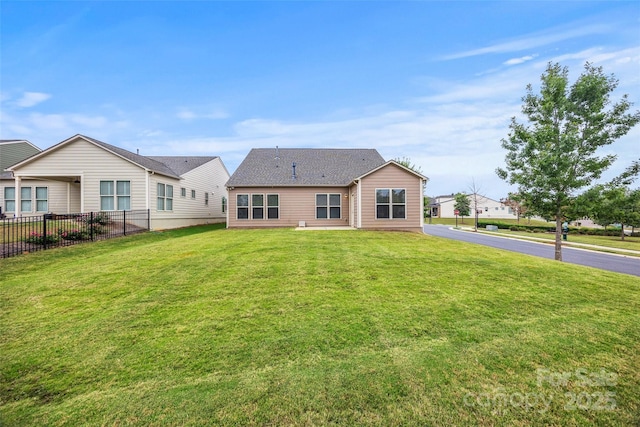 rear view of house with a yard and fence