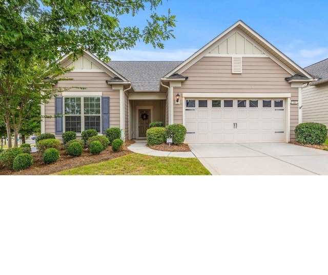 view of front of home with board and batten siding, concrete driveway, an attached garage, and a shingled roof