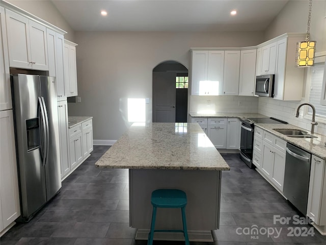 kitchen with sink, a kitchen island, decorative light fixtures, white cabinetry, and appliances with stainless steel finishes