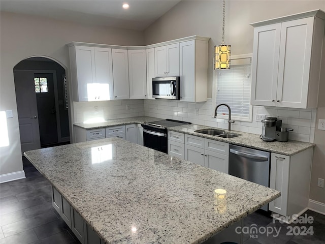 kitchen with white cabinets, sink, decorative light fixtures, appliances with stainless steel finishes, and a kitchen bar