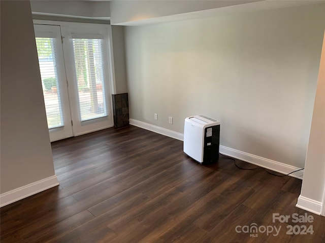 spare room featuring baseboards and dark wood-style flooring