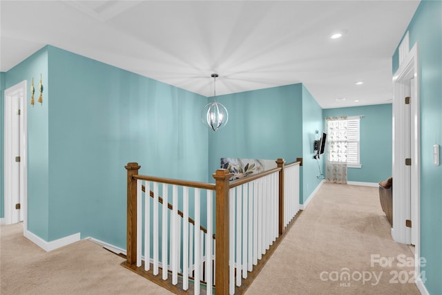 corridor featuring an inviting chandelier and light colored carpet