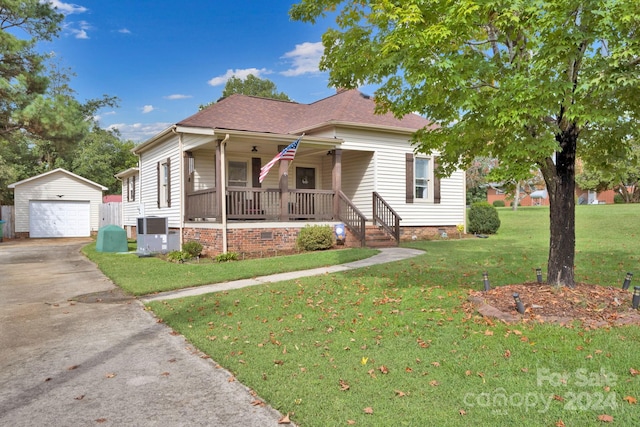 bungalow-style home with an outdoor structure, covered porch, a garage, central AC, and a front lawn