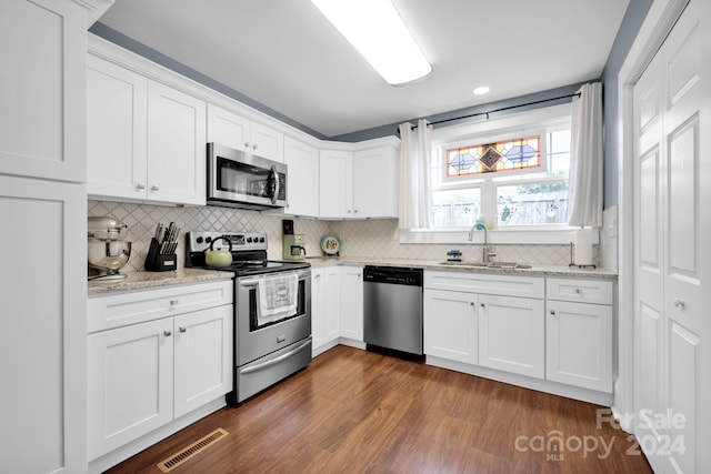 kitchen with appliances with stainless steel finishes, decorative backsplash, dark wood-type flooring, and white cabinets