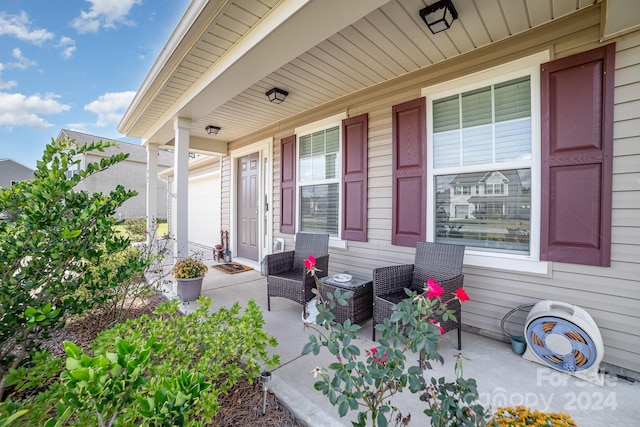 view of patio / terrace with a garage, central AC unit, and covered porch