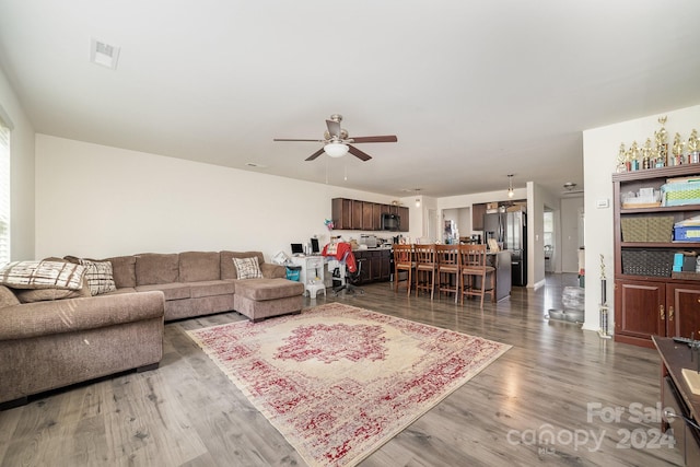 living room featuring a ceiling fan, wood finished floors, and visible vents