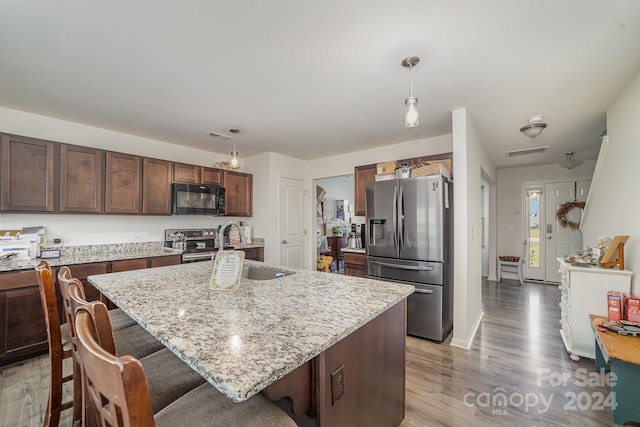 kitchen with visible vents, a kitchen bar, a sink, light wood-style flooring, and appliances with stainless steel finishes