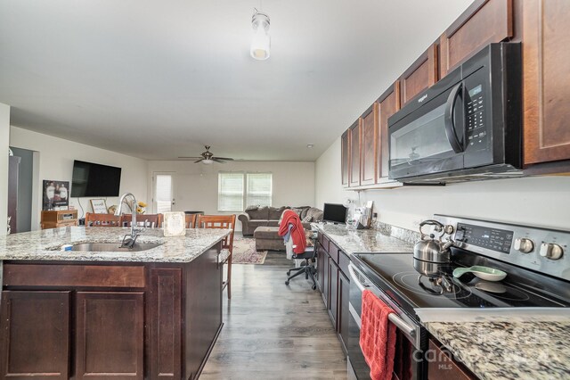 kitchen with black microwave, open floor plan, stainless steel electric range, and a sink