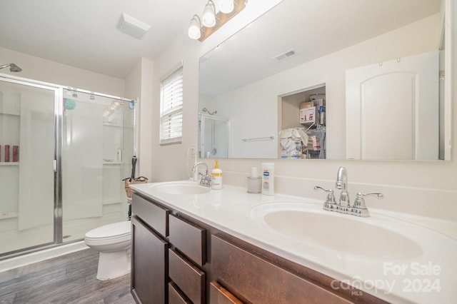 bathroom with a sink, a shower stall, wood finished floors, and visible vents
