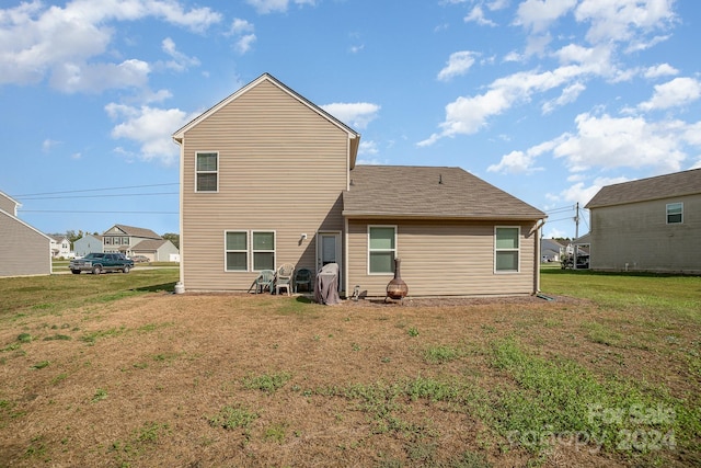 back of property with a yard and a shingled roof