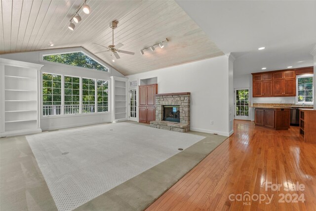 unfurnished living room featuring ceiling fan, wood ceiling, track lighting, a fireplace, and light wood-type flooring