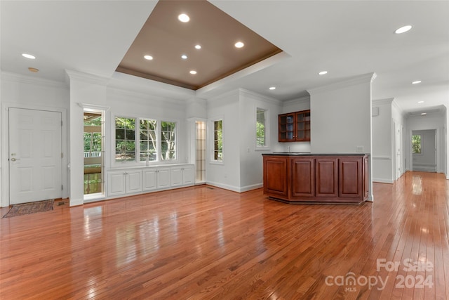 unfurnished living room with a healthy amount of sunlight, crown molding, and light hardwood / wood-style flooring