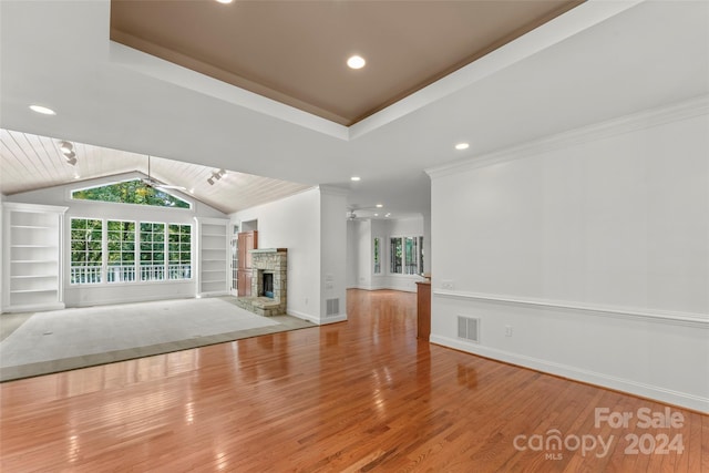 unfurnished living room with ornamental molding, a fireplace, hardwood / wood-style floors, and lofted ceiling