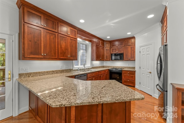 kitchen featuring light hardwood / wood-style flooring, black appliances, kitchen peninsula, and light stone countertops