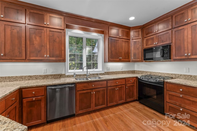 kitchen featuring black appliances, sink, light hardwood / wood-style flooring, and light stone countertops