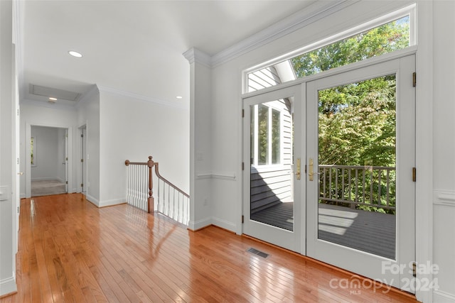 doorway featuring light hardwood / wood-style flooring, ornamental molding, and a wealth of natural light