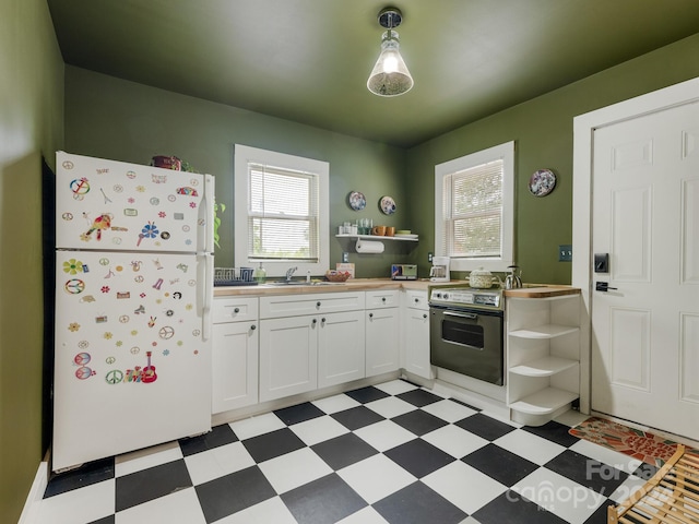 kitchen with white cabinets, white refrigerator, stainless steel electric stove, and sink