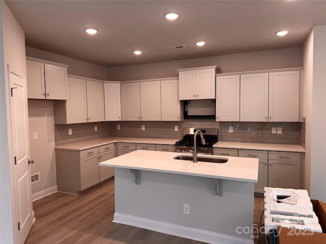 kitchen featuring white cabinets, sink, and a kitchen island with sink