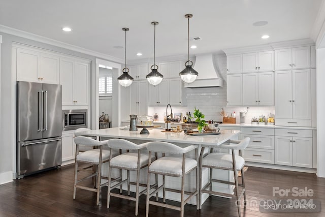 kitchen with an island with sink, white cabinets, pendant lighting, stainless steel appliances, and custom exhaust hood