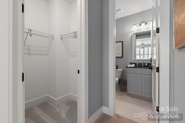 walk in closet featuring sink and light colored carpet