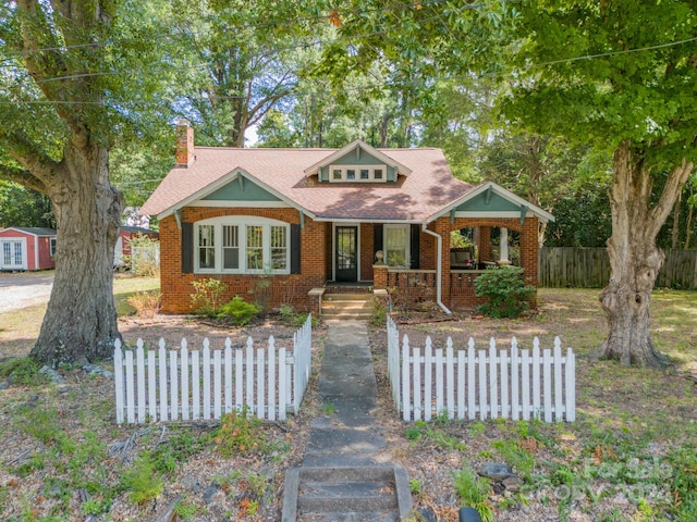 bungalow-style house featuring a porch and a shed