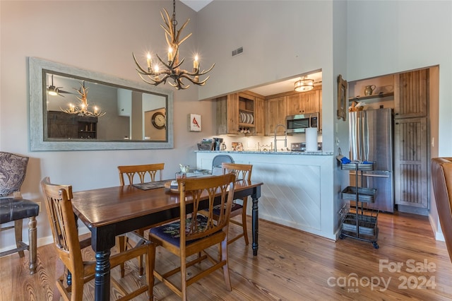 dining space with a high ceiling, hardwood / wood-style floors, and a chandelier