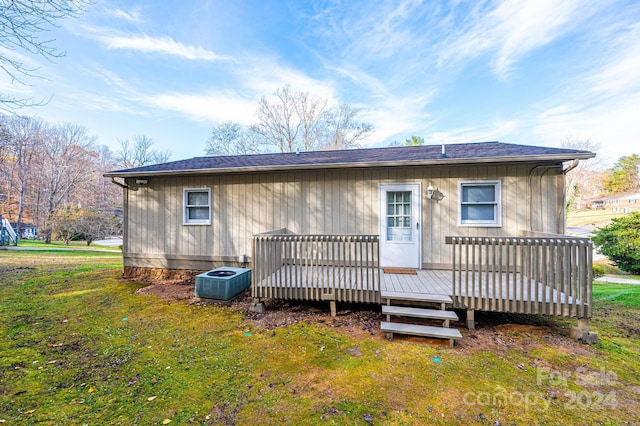 rear view of property featuring a lawn, central AC unit, and a deck