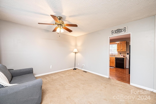 living area featuring light carpet, ceiling fan, and a textured ceiling