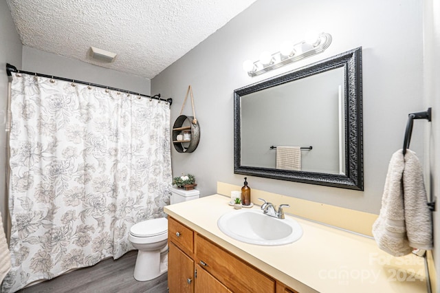 bathroom with toilet, vanity, a textured ceiling, and hardwood / wood-style flooring