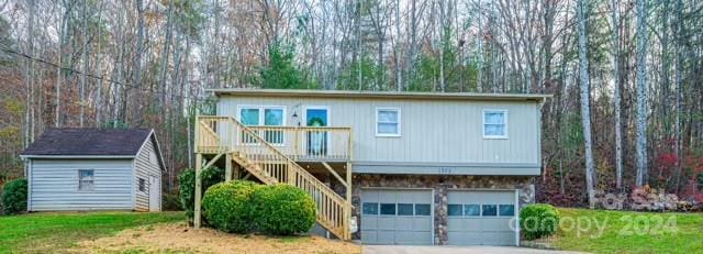 view of front of home featuring a front yard, a shed, a garage, and a wooden deck