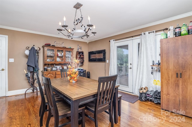 dining room with an inviting chandelier, light hardwood / wood-style flooring, and crown molding