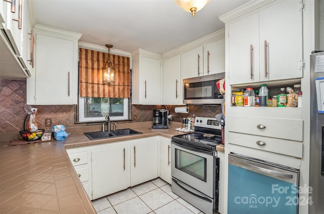 kitchen featuring hanging light fixtures, sink, white cabinetry, stainless steel appliances, and tile countertops