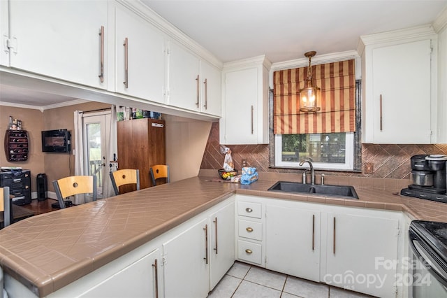 kitchen with pendant lighting, tile countertops, sink, and white cabinetry