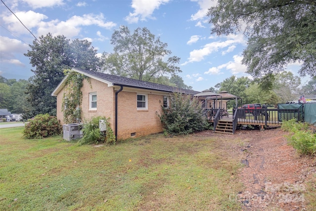 exterior space with central air condition unit, a deck, and a yard