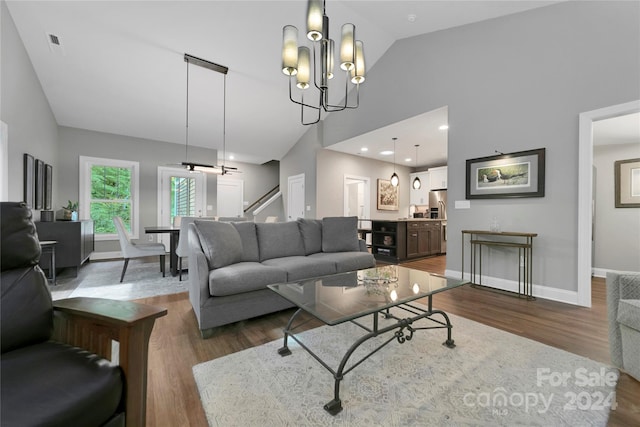 living room with high vaulted ceiling, hardwood / wood-style floors, and an inviting chandelier