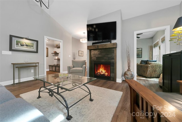 living room featuring a tiled fireplace, vaulted ceiling, and dark hardwood / wood-style flooring